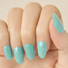 Close- up of a hand with teal turquoise glittery LED gel strips on nails on a beige background