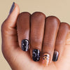 Hand with black and orange glitter halloween nail art on LED gel strips