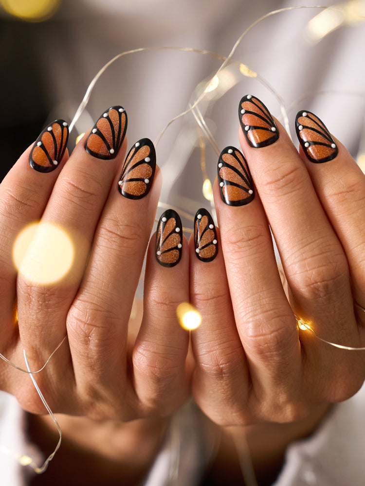 Close-up of magnetic butterfly-inspired coffin press-on nails with orange and black wing design.