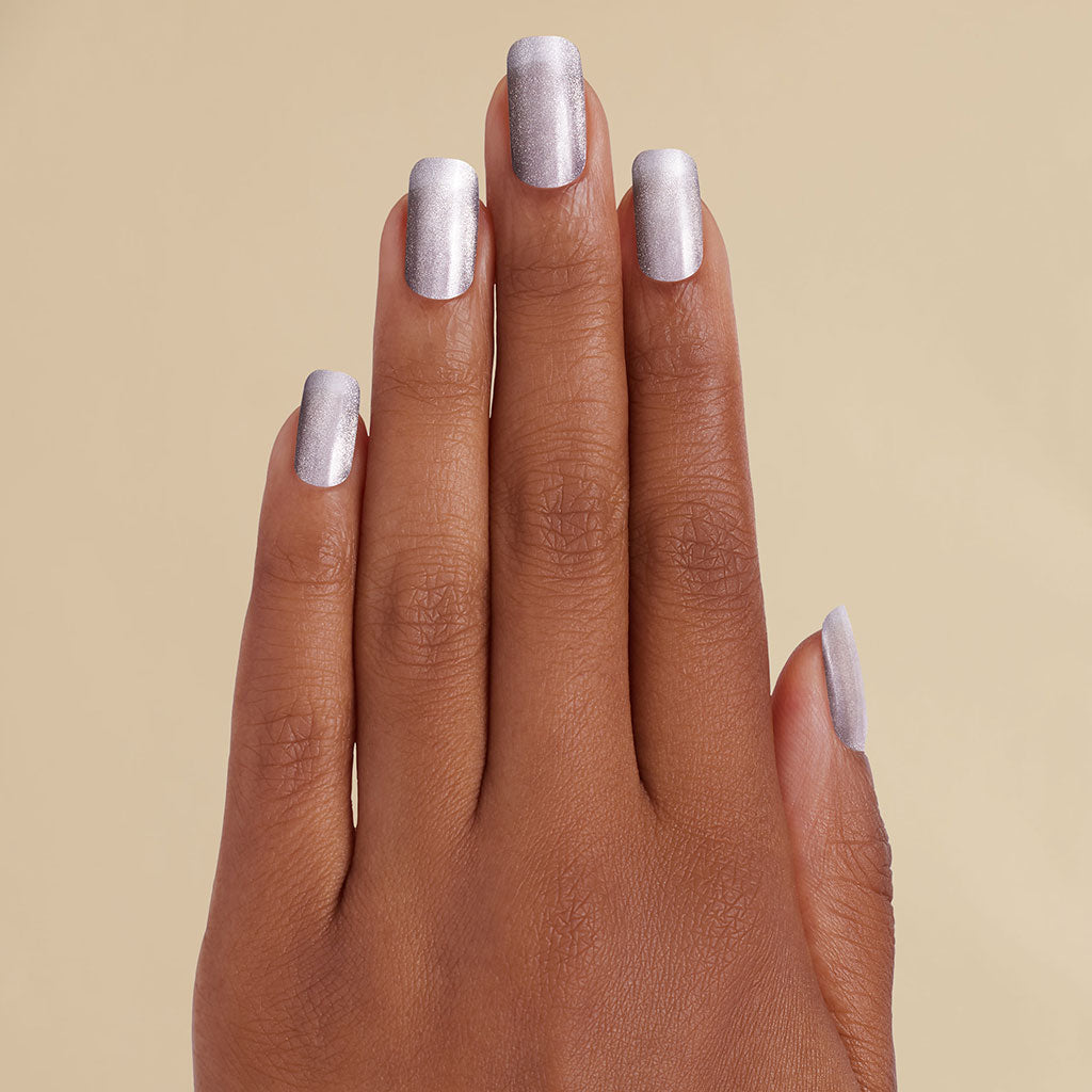 Hand with silver metallic LED gel strips on beige background