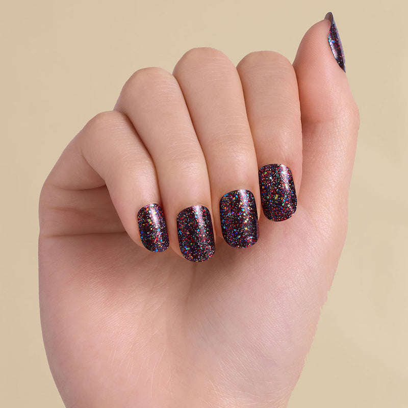 Hand with black multi colored glitter LED gel strips on beige background