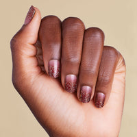 Hand with burgundy red ombre glitter LED gel strip nails on beige background