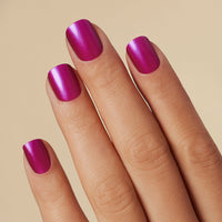 Close-up of a hand with bright pink short square press on gel nails on a beige background