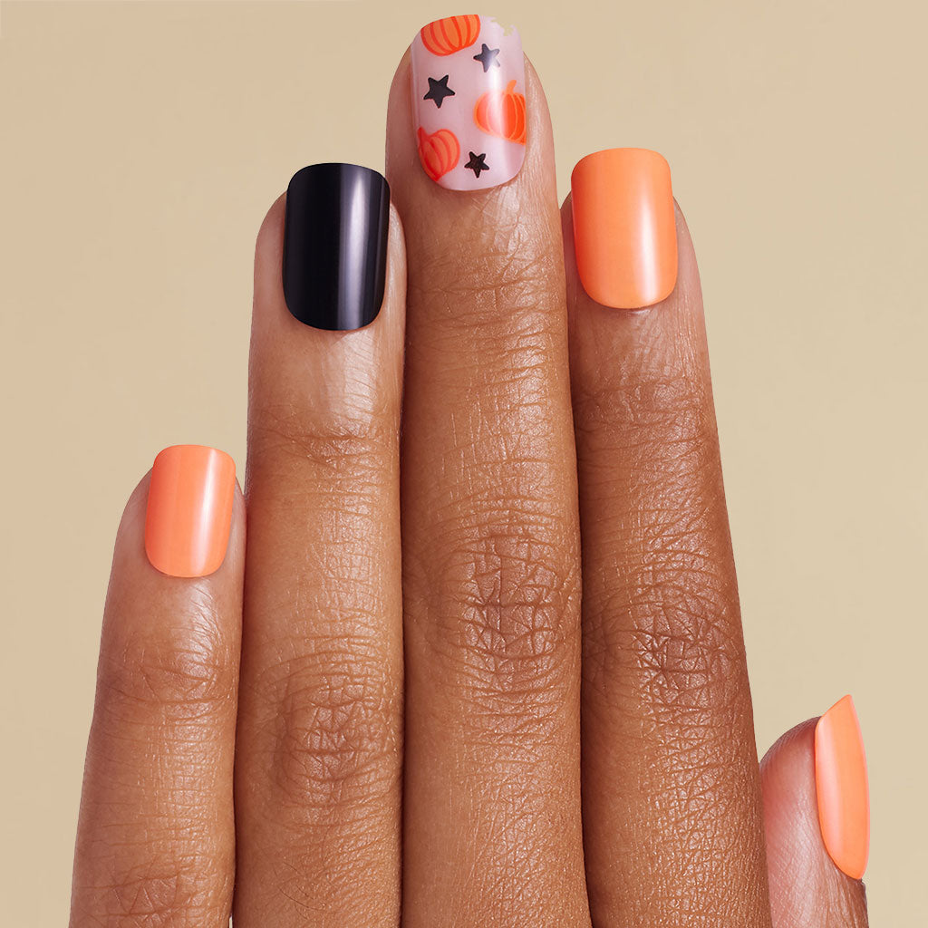 Hand with orange and black nail art on a beige background