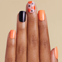 Hand with orange and black nail art on a beige background