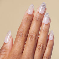 Hand with silver glitter almond press on nails with beige background