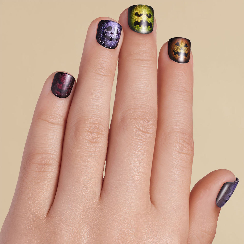 Kid's hand with Halloween-themed nail art on press on nails