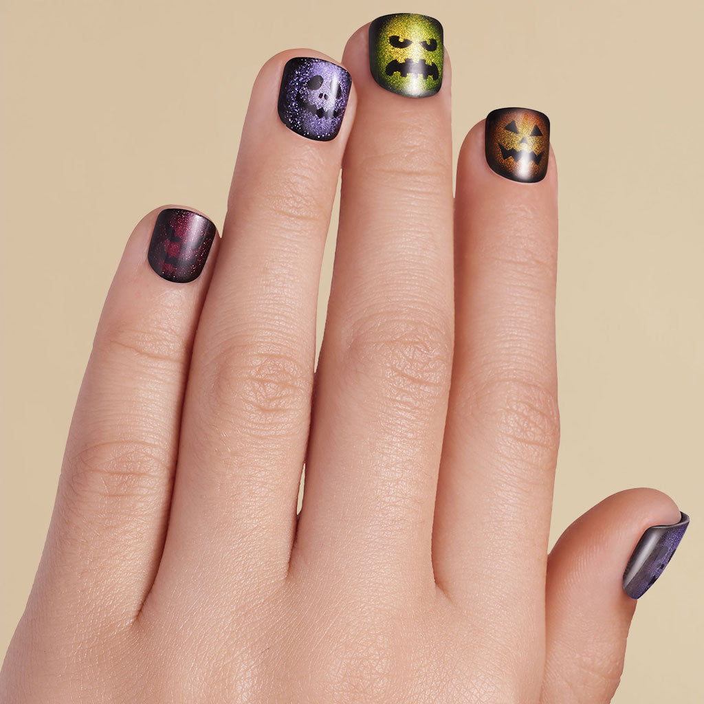 Kid's hand with Halloween-themed nail art on press on nails