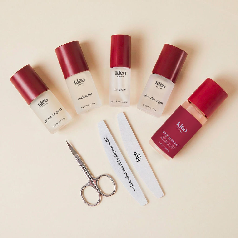 Set of Kleo nail care products including bottles and a pair of scissors on a beige background