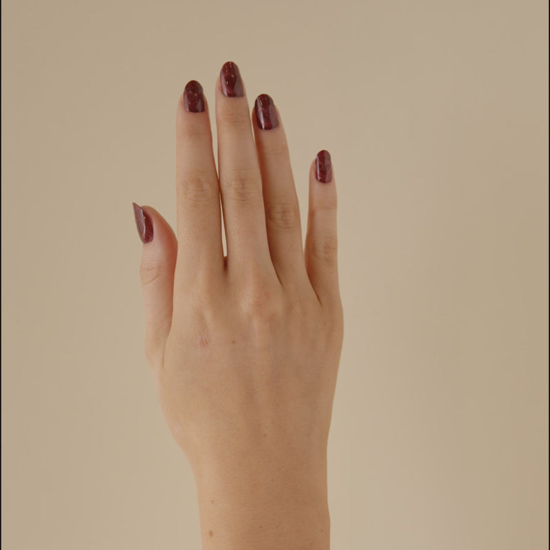 Hand with glittery red burgundy heart magnetic valentine day LED gel strip nails showing the magnetic effect